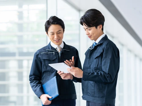 タブレットを持って打ち合わせをする男性二人の写真